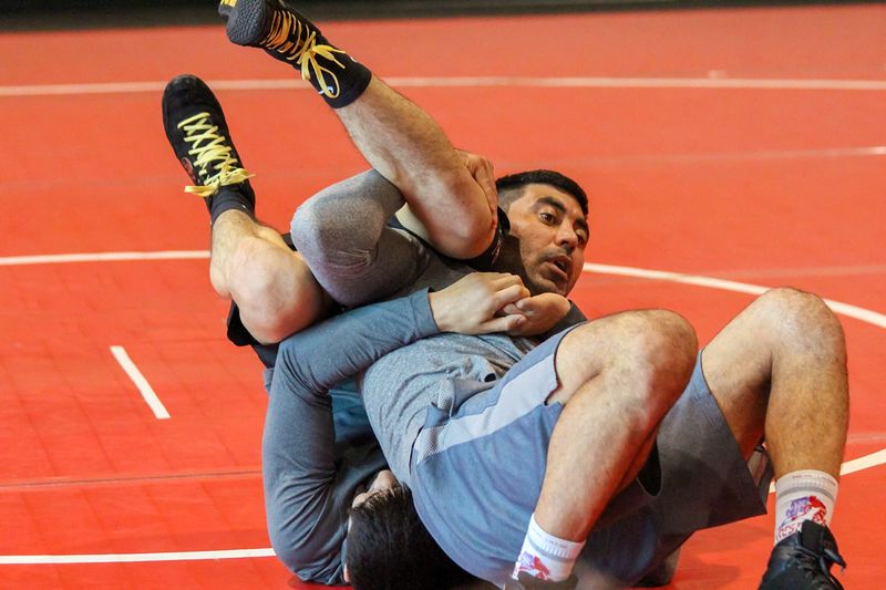 Two coaches demonstrating mat wrestling on the red mat at Ken Chertow's summer wrestling camp