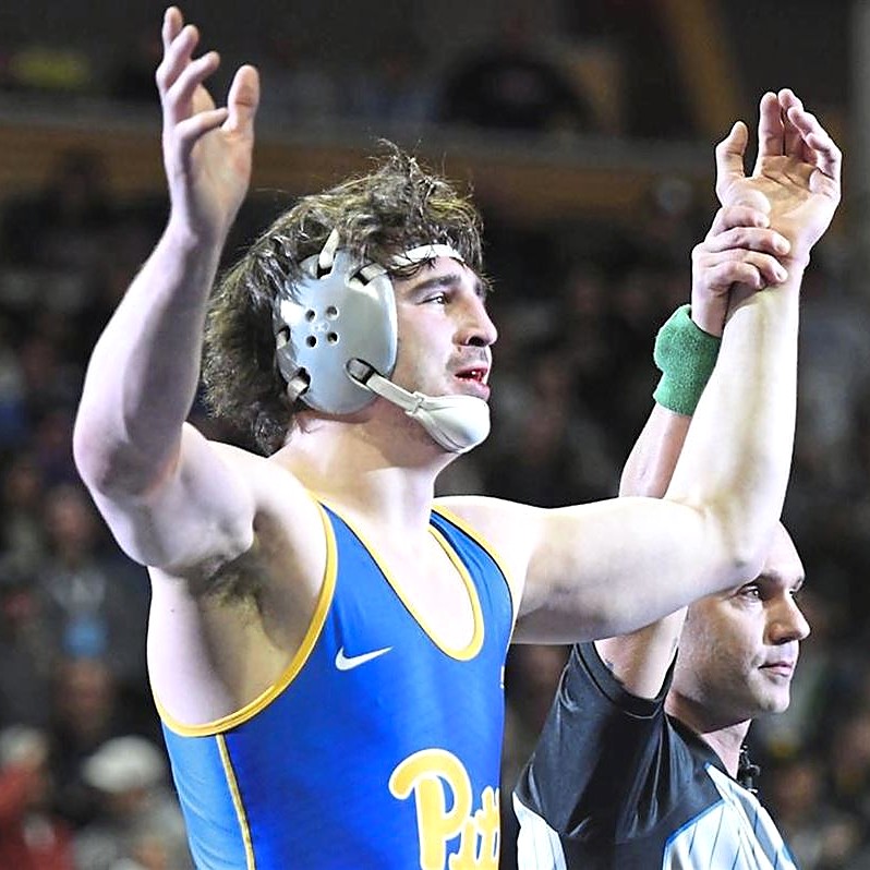 Nino Bonaccorsi in a Pitt singlet, arms up as the referee raises his hand, coach at Ken Chertow's summer wrestling camp
