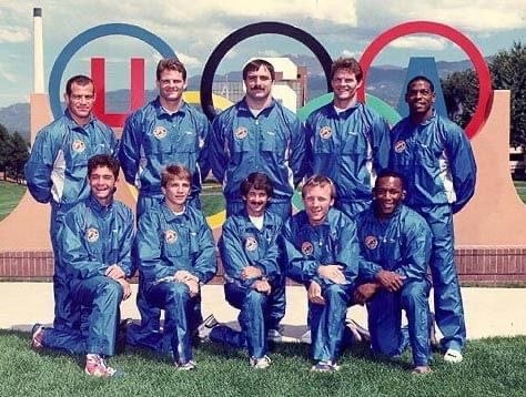 The USA Olympic wrestling team in blue warm-ups in front of the Olympic rings