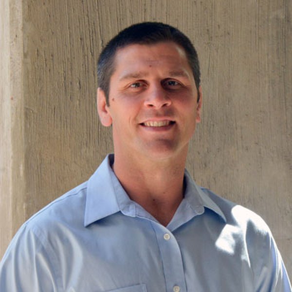 Dr. James Yonushonis, smiling, in a light-blue button-down shirt, on the staff at Ken Chertow's summer wrestling camp