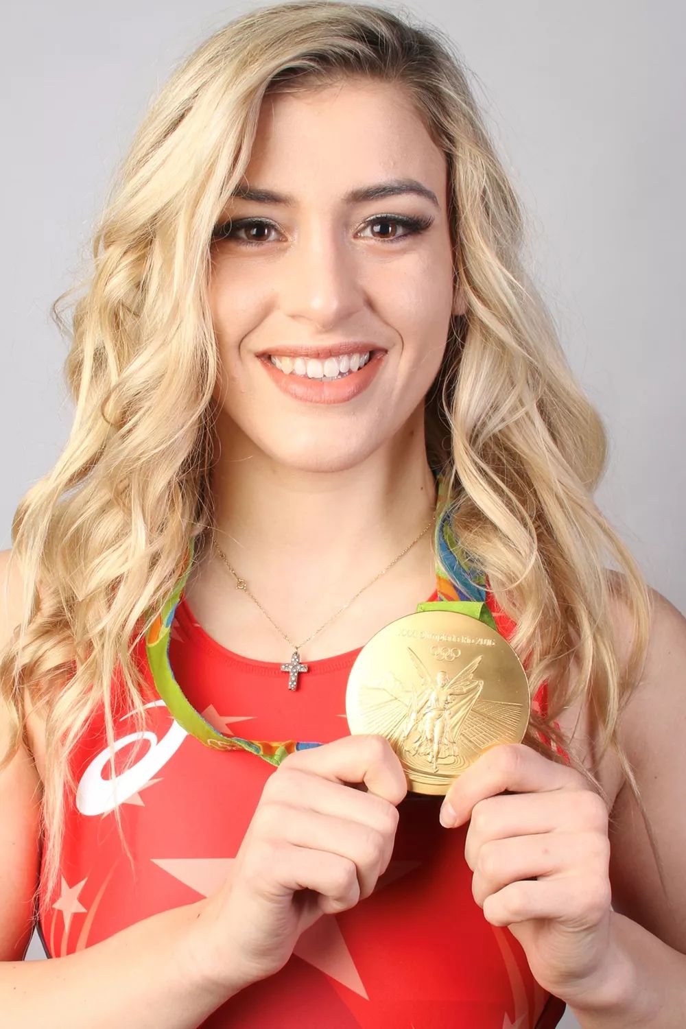 Helen Maroulis smiling and holding up her Olympic gold medal