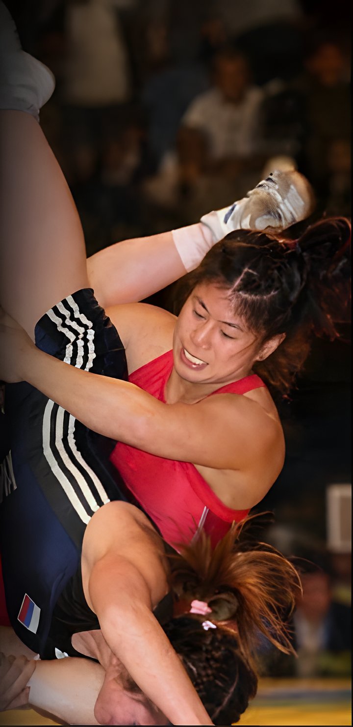 Jenny Wong in a red singlet on top of her opponent during a wrestling match