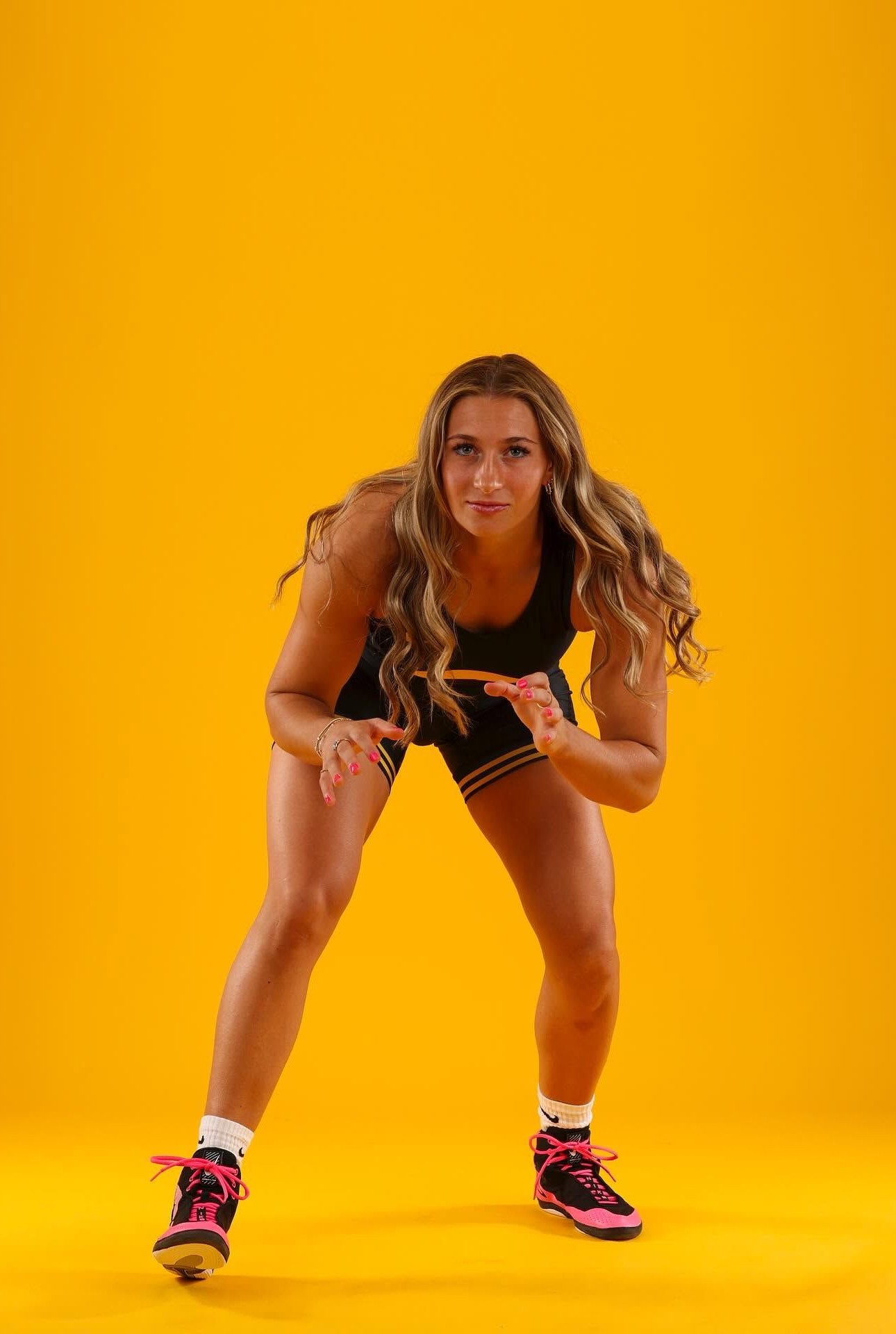 Kylie Welker in a low wrestling stance against a yellow backdrop