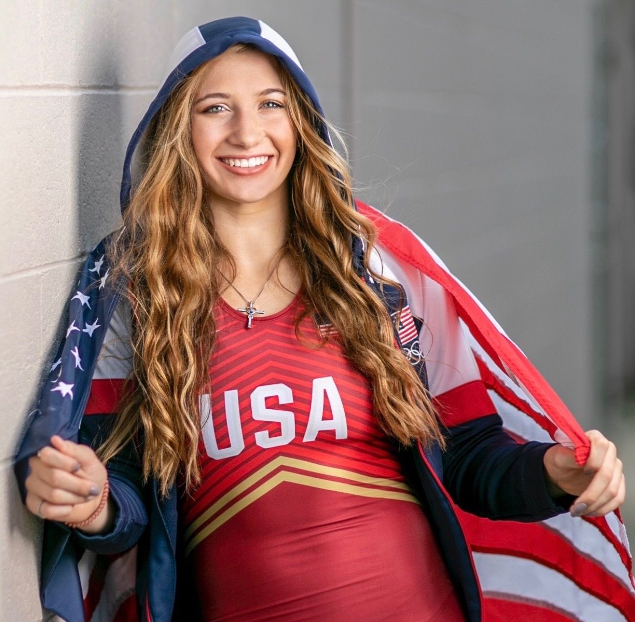 Kylie Welker smiling in a red USA singlet with an American flag around her shoulders