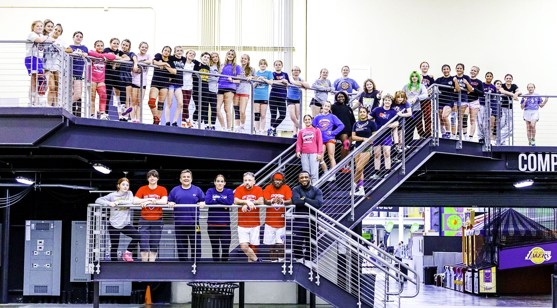 Girls wrestling camp campers lined up along a balcony and stairway at Spooky Nook Sports, staff below