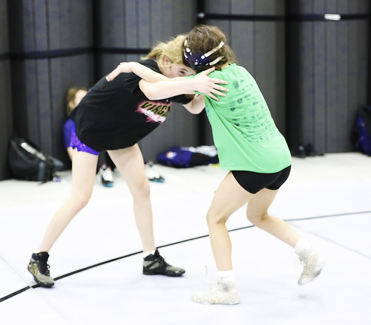 Two girls hand-fighting on the mat at Ken Chertow's SuperGirl girls wrestling camp