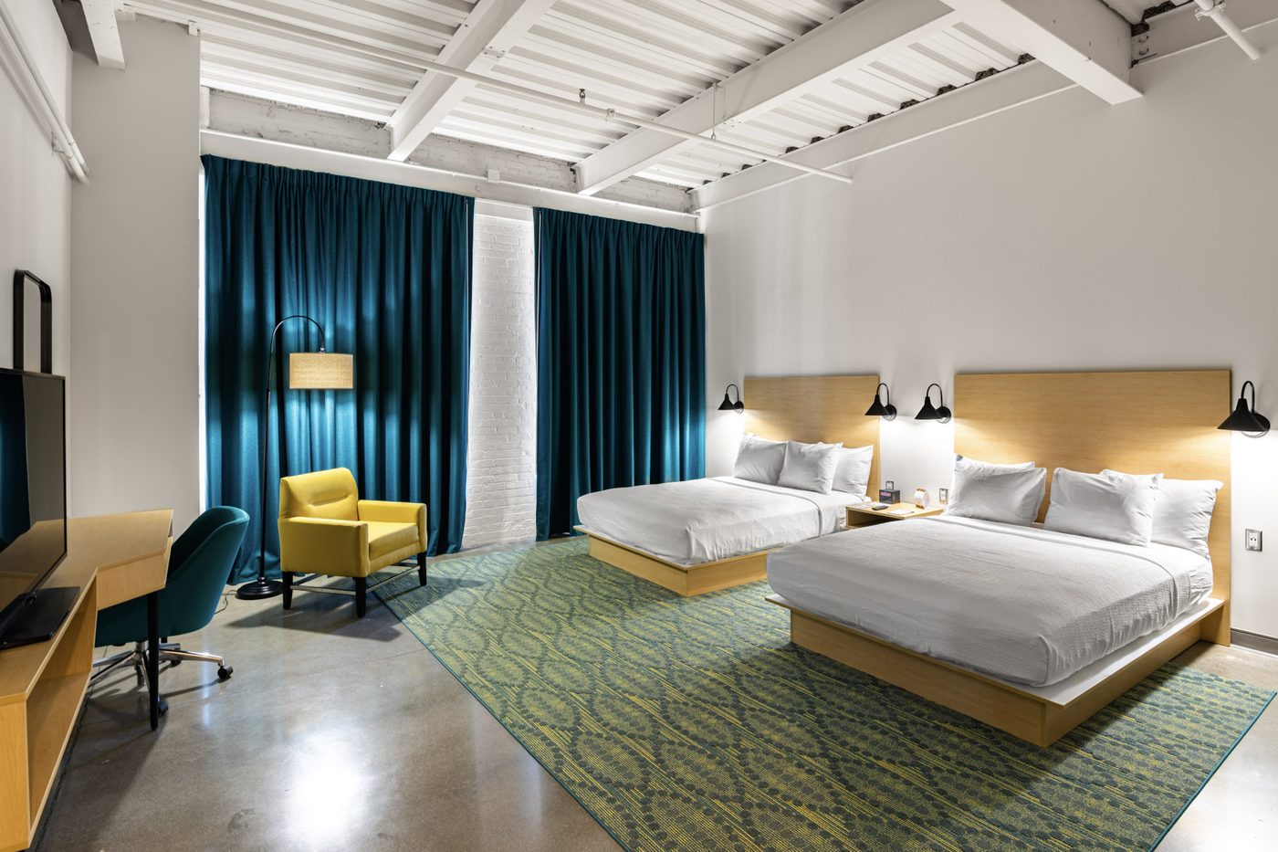 A Warehouse Hotel room with two queen beds and teal curtains for SuperGirl girls wrestling summer camp families